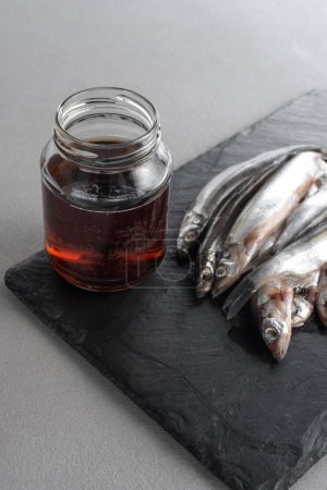 Photo for Garum is a fermented fish sauce. Prepared by fermentation from fish, salted garum sauce in a bottle on a gray background. Garum fish sauce made from anchovies on the grey background. - Royalty Free Image