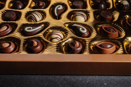 Photo for A box of different chocolates. Chocolate assortment mix on the black table, top view. - Royalty Free Image