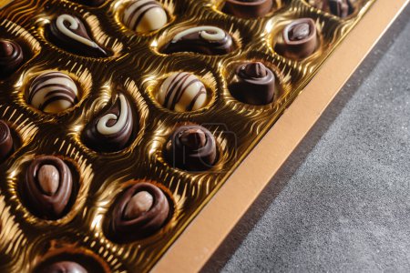 Photo for A box of different chocolates. Chocolate assortment mix on the black table, top view. - Royalty Free Image