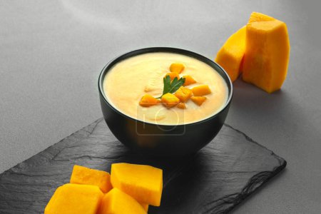 Photo for Pumpkin cream soup mashed potatoes on a gray background. Vegan curried pumpkin lentil soup puree in a bowl. Space for text. Pescatarian Eating, Flexitarian Eating, Reducetarian Eating - Royalty Free Image