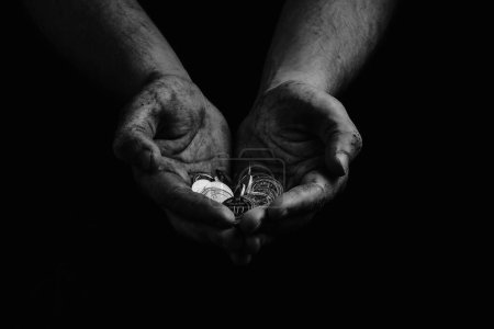 Foto de Pobreza en Ucrania. Blanco y negro. Sucias manos de un pobre vagabundo sosteniendo grivnias ucranianas en monedas. - Imagen libre de derechos