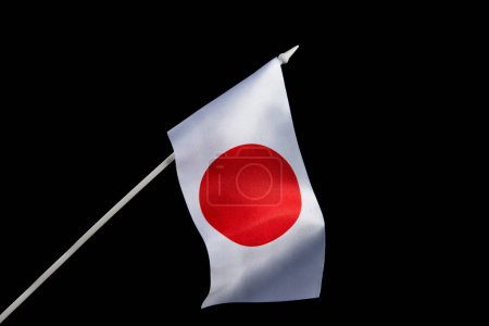 Photo for The Japanese flag on a black background developing and flying in the wind. - Royalty Free Image
