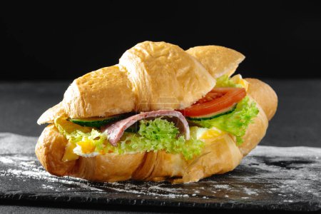 Photo for Croissant sandwich with sausage on a dark background. - Royalty Free Image