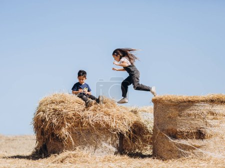 Téléchargez les photos : Enfants jouant sur des balles de foin - en image libre de droit