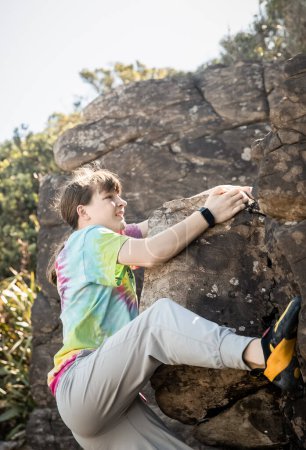 Téléchargez les photos : Young teen girl climbing bouldering on natural cliff, outdoor bouldering activity. High quality photo - en image libre de droit