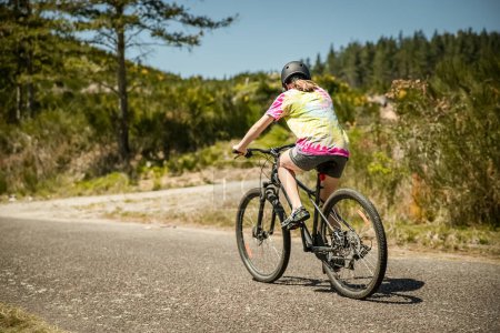 Téléchargez les photos : Portrait en plein air d'une fille blanche heureuse en vélo sur fond naturel. Photo de haute qualité - en image libre de droit