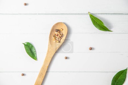 Photo for Various spices on a wooden spoon on white wooden background with other white kitchenware and green leaves. High quality photo - Royalty Free Image