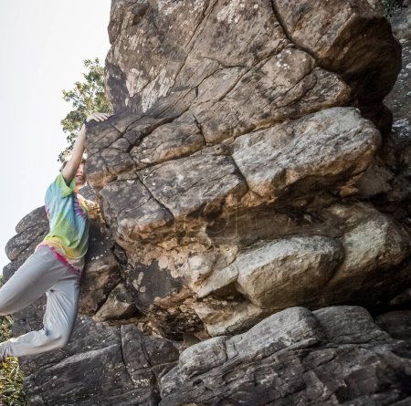 Téléchargez les photos : Young teen girl climbing bouldering on natural cliff, outdoor bouldering activity. High quality photo - en image libre de droit