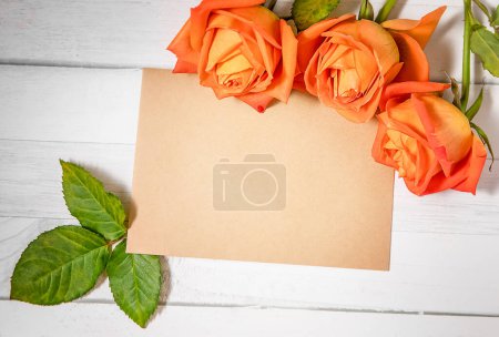 Photo for An empty message note with fresh flower roses isolated over white wooden background. High quality photo - Royalty Free Image
