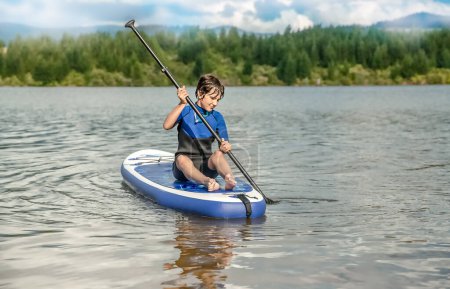 Téléchargez les photos : Active teen girl paddling a sup board on a river or lake, natural background, active healthy sporty lifestyle. High quality photo - en image libre de droit