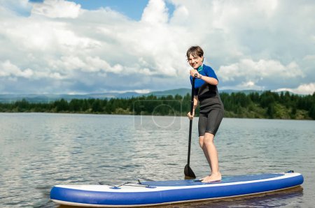 Photo for Active teen girl paddling a sup board on a river or lake, natural background, active healthy sporty lifestyle. High quality photo - Royalty Free Image