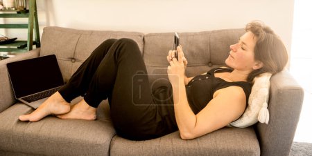 Photo for Girl holding cell phone in home environment, work from home, relaxed business concept. - Royalty Free Image