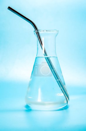 Foto de Líquido transparente con burbujas de agua en un frasco de laboratorio de vidrio, botella isoalted sobre fondo azul. Foto de alta calidad - Imagen libre de derechos