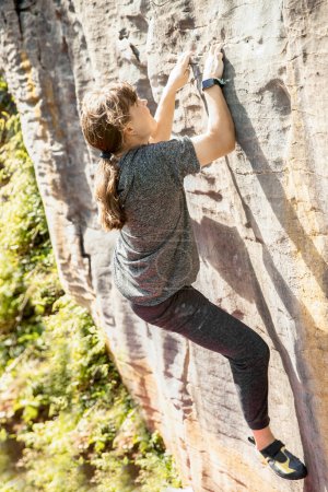 Photo for Young active teen girl doing outdoor rock climbing bouldering on natural cliff. High quality photo - Royalty Free Image