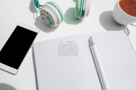 Photo for Phone, head phones, note and stationery isoalted over background, business or educational tools, wok from home concept. High quality photo - Royalty Free Image