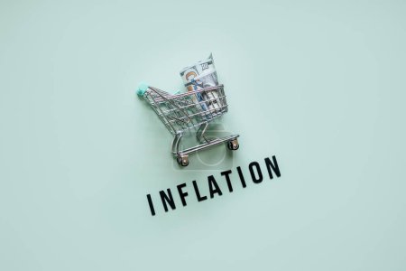 Warenkorb mit Dollar Bargeld und Wort Inflation auf blauem Hintergrund. Inflation Finanzkrise und steigende Rohstoffpreise Konzept. Steigende Lebenskosten