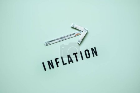 Concepto de crisis financiera de inflación. Creciendo flecha de billete de dólar y palabra Inflación sobre fondo azul. Aumento del coste de vida