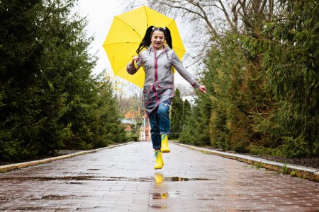 Photo for Autumn depression and how to deal with it. Seasonal affective disorder SAD. Happy senor woman in yellow rain boots and umbrella having fun and enjoy life in rainy autumn park. - Royalty Free Image