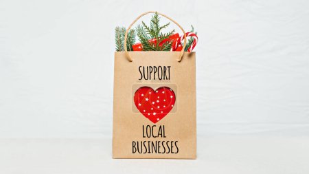 Support Local Business text written on paper shopping bag. Support Local Business quote, Christmas decoration and shopping bag, gift boxes and staff