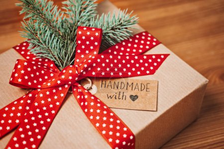 Téléchargez les photos : Aucun cadeau Idées de Noël pour la famille, Amis pour un Noël anti-consumériste. Boîte en papier kraft cadeau de Noël avec ruban rouge, sapin et étiquette d'amour faite à la main sur table en bois. - en image libre de droit