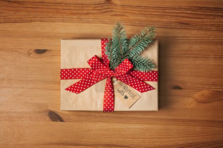 Téléchargez les photos : Aucun cadeau Idées de Noël pour la famille, Amis pour un Noël anti-consumériste. Boîte en papier kraft cadeau de Noël avec ruban rouge, sapin et étiquette d'amour faite à la main sur table en bois. - en image libre de droit