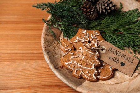 Téléchargez les photos : Cadeaux de Noël bon marché, Idées cadeaux pas cher budget de Noël. Biscuits au pain d'épice maison de Noël avec ruban, sapin et étiquette d'amour faite à la main sur une table en bois. - en image libre de droit