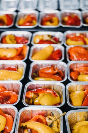 Photo for Pre-portioned Gourmet Roasted Bell Peppers in Trays. Close-up view of vibrant roasted bell peppers portioned in aluminum trays, prepared for a catered event or meal service - Royalty Free Image