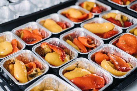 Photo for Pre-portioned Gourmet Roasted Bell Peppers in Trays. Close-up view of vibrant roasted bell peppers portioned in aluminum trays, prepared for a catered event or meal service - Royalty Free Image