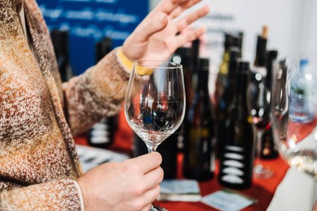 Los visitantes profesionales que participan en la conversación y la creación de redes, con uno sosteniendo una copa de vino, en el mundo líder en la feria del vino.