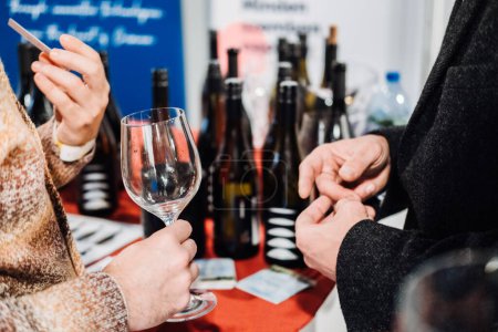 Los visitantes profesionales que participan en la conversación y la creación de redes, con uno sosteniendo una copa de vino, en el mundo líder en la feria del vino.