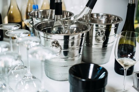 Une élégante station de dégustation de vin avec des bouteilles réfrigérées dans des seaux à glace et des verres à l'envers, attendant les visiteurs professionnels à une foire aux vins.
