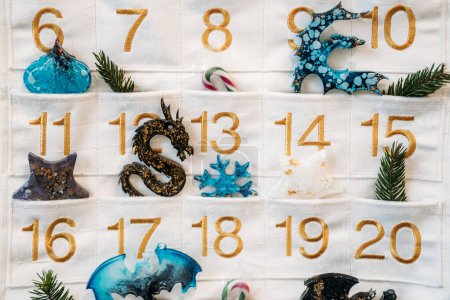 Festive advent calendar displaying days with pockets filled with unique epoxy resin charms and holiday motifs, ready for the Christmas countdown.