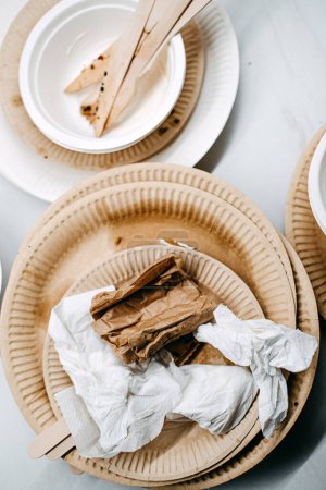 Foto de Placas biodegradables y utensilios de madera usados en una mesa, destacando la opción ecológica para vajilla desechable después de una comida. - Imagen libre de derechos