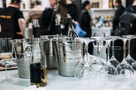Eine elegante Weinverkostungsstation mit gekühlten Flaschen in Eimern und umgedrehten Gläsern erwartet die Fachbesucher auf einer Weinmesse.