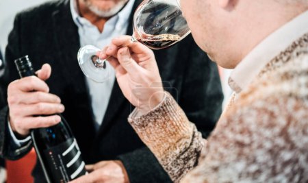 Trade visitors engaging in conversation and networking, with one holding a wine glass, at the worlds leading wine fair.