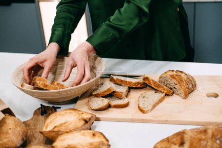 Mains en ordre délicat tranches de pain au levain fraîchement cuit dans un bol, mettant en valeur l'art de la fabrication du pain traditionnel.
