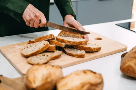 Hands gently arranging slices of freshly baked sourdough bread in a bowl, showcasing the art of traditional bread making.