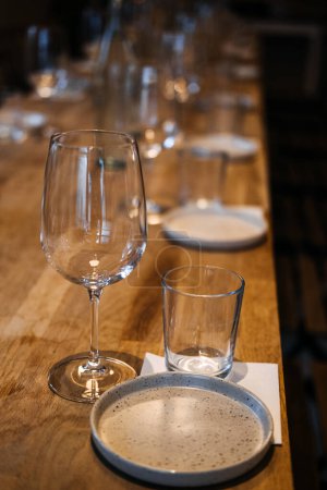 Una larga mesa de madera en una bodega con elegantes copas de vino, lista para una experiencia profesional de cata de vinos.