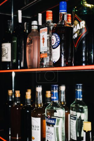 Téléchargez les photos : Un affichage bien éclairé de divers spiritueux, avec diverses bouteilles sur des étagères de bar éclairées, offrant une sélection pour tous les goûts des connaisseurs. - en image libre de droit