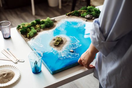 Téléchargez les photos : Art en résine époxyde 3D finement conçu avec un magnifique paysage côtier, exposé sur une table d'atelier, mettant en valeur les compétences et la créativité des artistes. - en image libre de droit