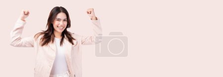 Excited young business woman raised hands celebrating success Portrait cheerful positive mix race female with raised hands and fists open mouth Girl get happy, enjoy life isolated on pink copy space
