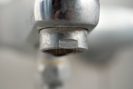 Old lime scale or calcium stained bathtub faucet from hard water. Close up detail shot, shallow depth of field, no people.