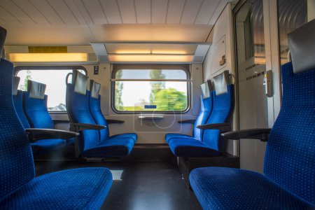 Train de voyageurs avec sièges vides. Longue exposition grand angle, fond vert flou par la fenêtre d'un train vide en Suisse, Europe, pas de personnes.