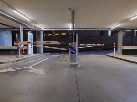 Photo for Underground large car park entrance and exit lanes with ticket dispensers and barriers. No people. - Royalty Free Image