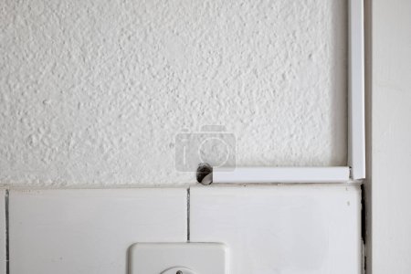 Weiße Kunststoff-Kabelkanaldeckel an einer Küchenwand. Nahaufnahme, keine Menschen.