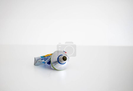 Used up squeezed out metal paste tube ready for recycling close up studio shot isolated on white