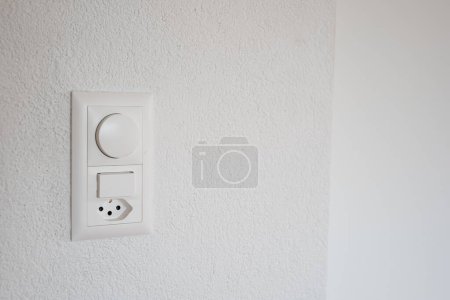 Wall mounted light switches and power outlet. Close up shot, no people.