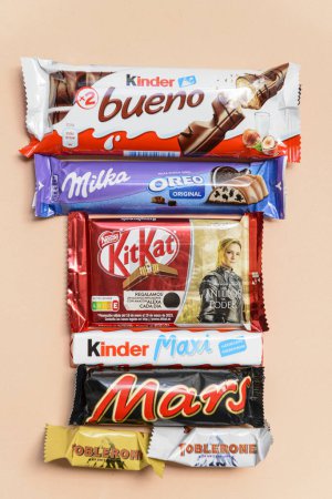 Photo for Arahal. Seville. Spain. March 18, 2023. Still life with chocolates bars of different brands on light orange background . Excessive consumption of sugar can have negative consequences on health. - Royalty Free Image