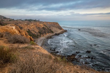 As the sun sets over Golden Cove, its tranquil waters reflect the warm hues of the sky, offering a serene escape amidst the rugged cliffs of Rancho Palos Verdes, California.