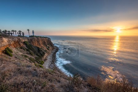 Tranquilo atardecer pinta el cielo sobre Point Vicente, proyectando tonos dorados sobre la escarpada costa, un momento sereno en Rancho Palos Verdes, California.
